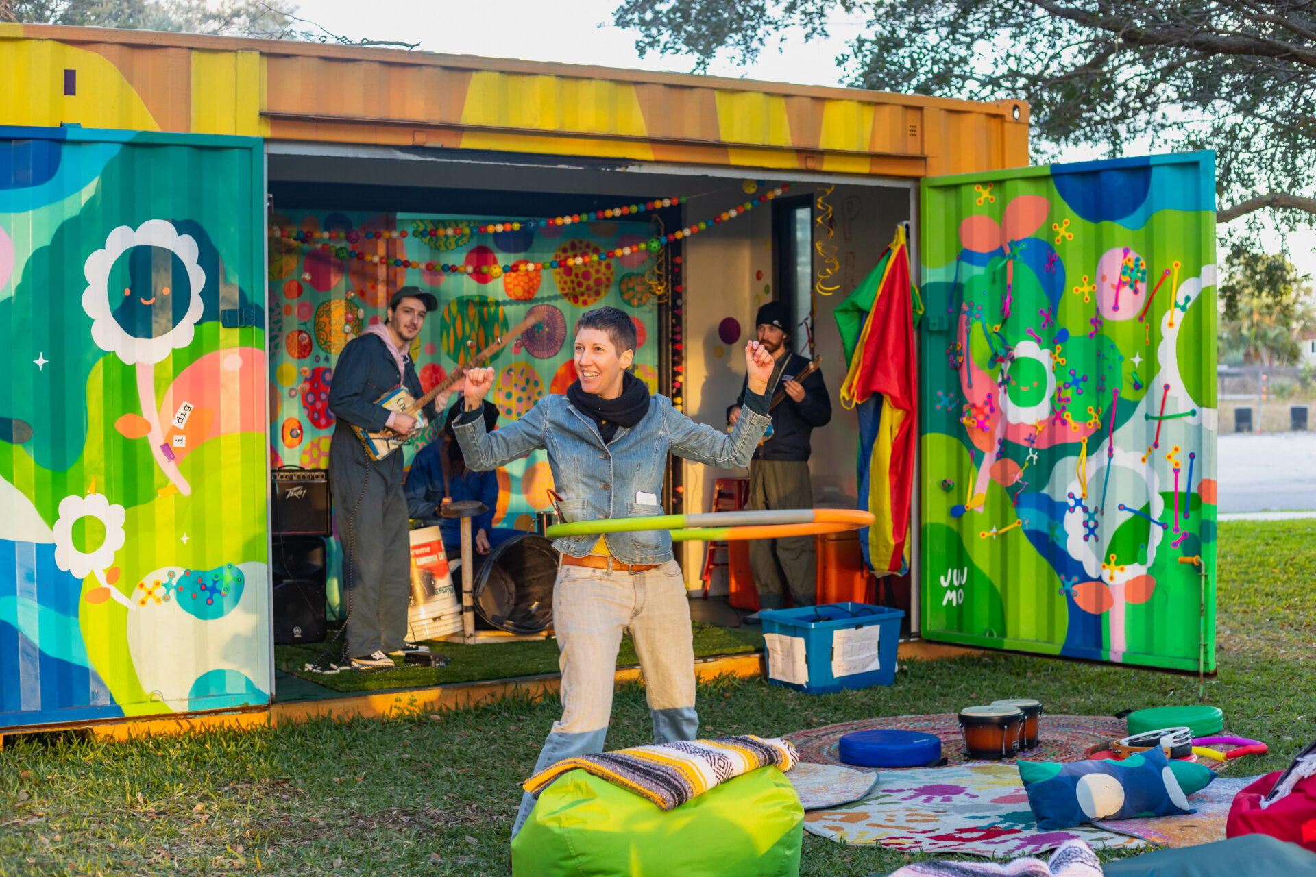 PT Creative District Manager Mitzi Gordon at the closing party for SPACEcraft in Florida. Gordon is hula hooping in front of an open shipping container, covered in vibrant murals. A band is playing inside the container.